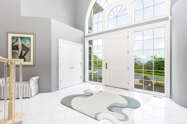 tiled foyer entrance featuring plenty of natural light, baseboards, and a high ceiling