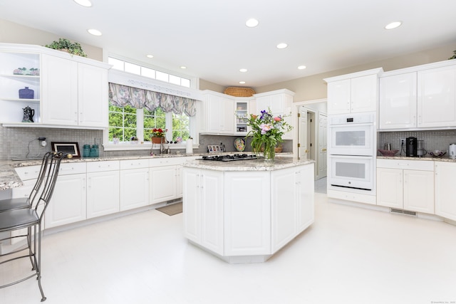 kitchen featuring white double oven, backsplash, gas stovetop, recessed lighting, and white cabinets