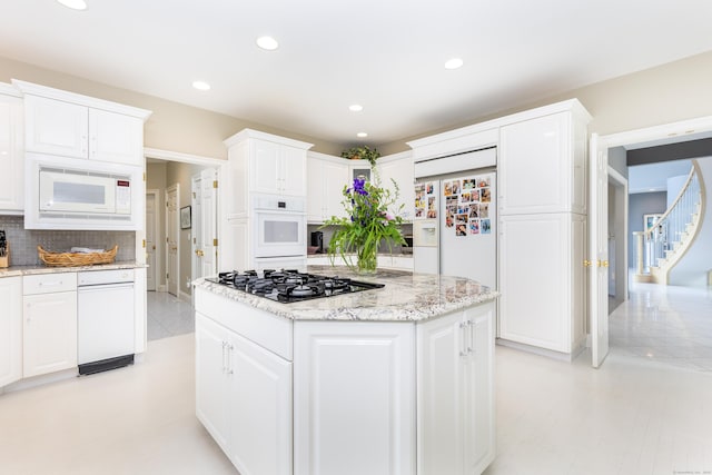 kitchen featuring white appliances, white cabinets, tasteful backsplash, a center island, and recessed lighting