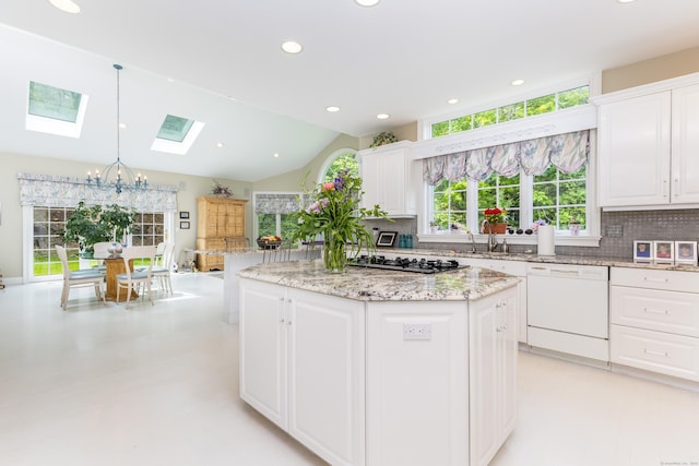 kitchen featuring dishwasher, a skylight, tasteful backsplash, a sink, and recessed lighting