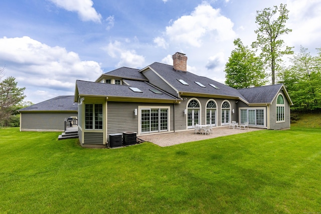 rear view of property featuring a yard, a chimney, a patio area, and central AC