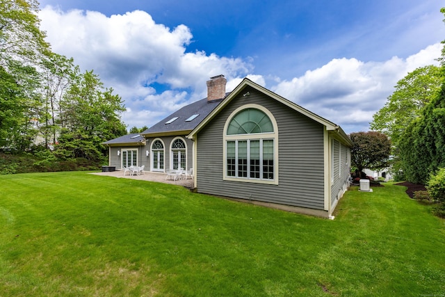 back of house with a patio, a chimney, a lawn, and cooling unit
