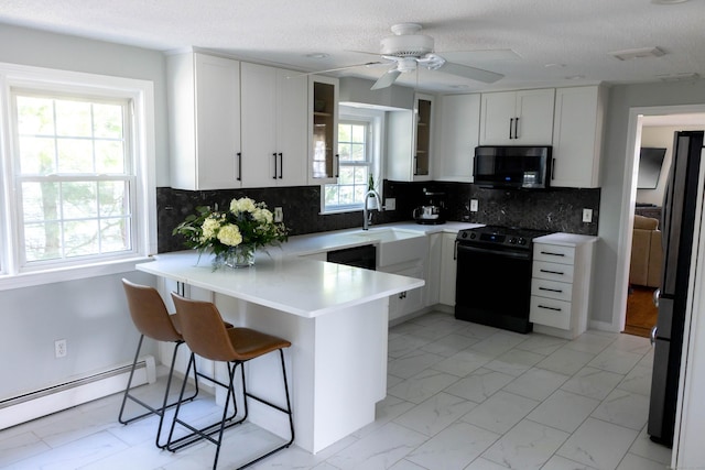 65 Lufkin Ln, Bristol, CT 06010 - kitchen with black electric range, stainless steel microwave, baseboard heating, a peninsula, and light marble finish flooring