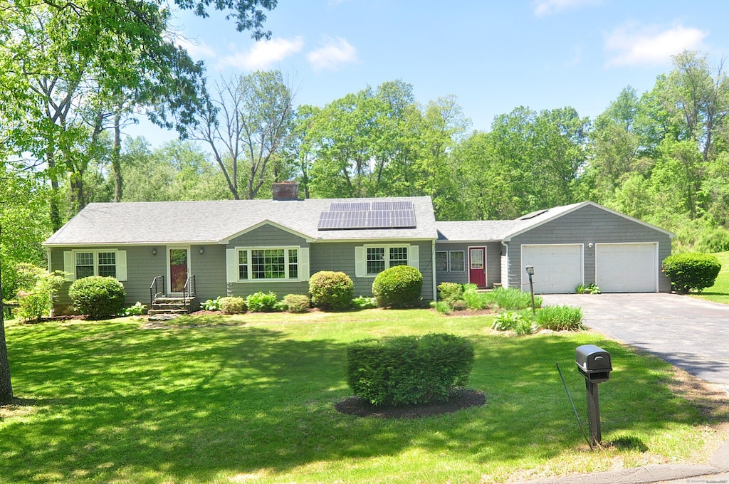 142 Case St, Canton, CT 06019 - single story home with an attached garage, roof mounted solar panels, asphalt driveway, a front lawn, and a chimney