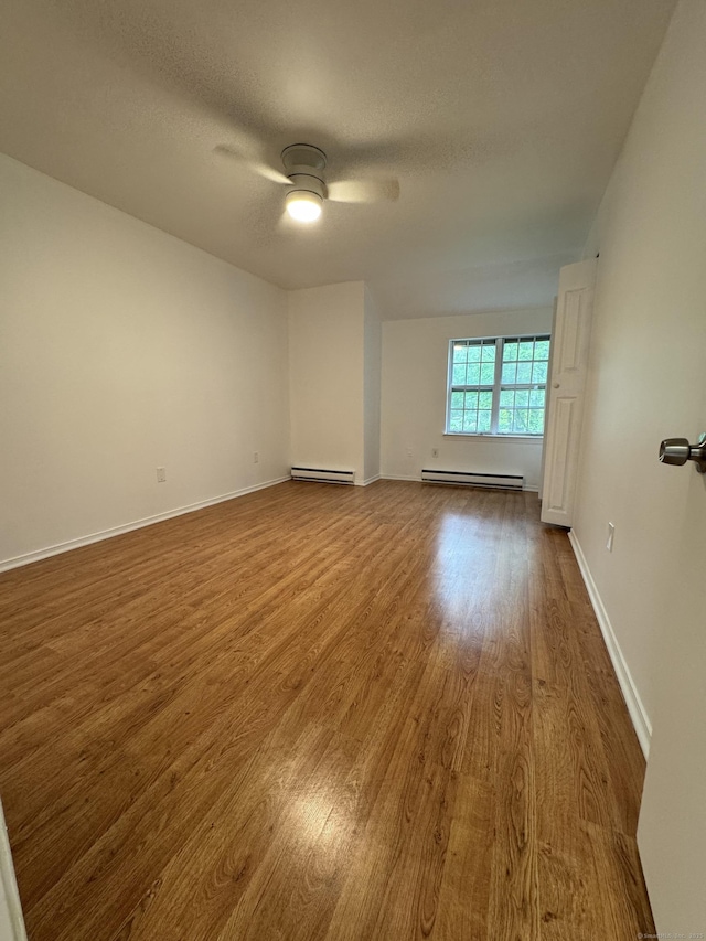 103 Kohanza St Unit E, Danbury, CT 06811 - unfurnished room featuring baseboard heating, wood finished floors, a ceiling fan, baseboards, and a textured ceiling