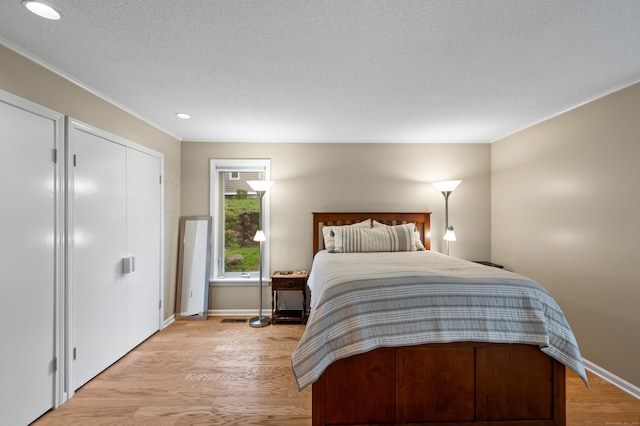 bedroom featuring crown molding, light wood-style floors, recessed lighting, a textured ceiling, and baseboards