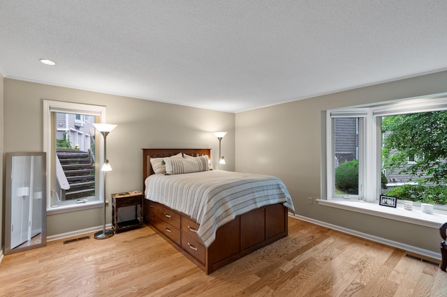 bedroom with light wood-style flooring, a textured ceiling, and baseboards