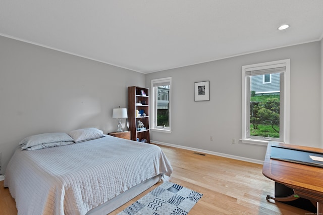 bedroom with multiple windows, baseboards, light wood finished floors, recessed lighting, and ornamental molding