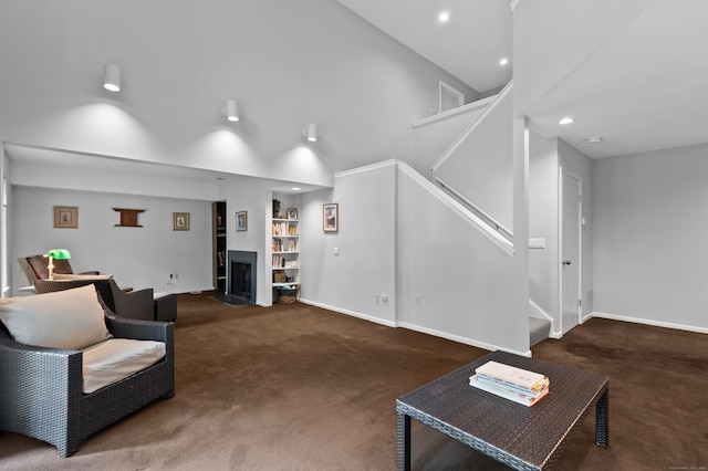 carpeted living room with stairway, baseboards, recessed lighting, built in shelves, and a high ceiling