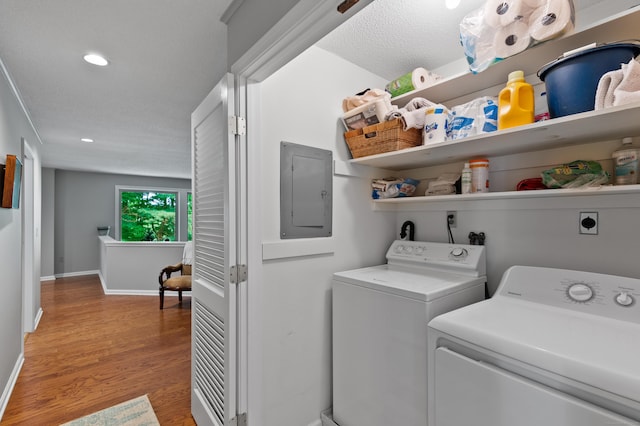 washroom with electric panel, independent washer and dryer, light wood-style floors, recessed lighting, and baseboards