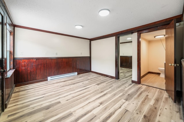 253 N Main St, Norwich, CT 06360 - unfurnished room with baseboard heating, light wood finished floors, a wainscoted wall, a textured ceiling, and wood walls