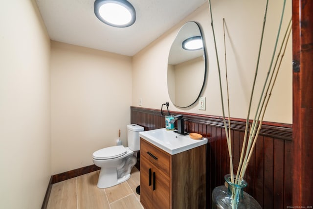 253 N Main St, Norwich, CT 06360 - bathroom with wainscoting, toilet, wood finished floors, vanity, and wooden walls