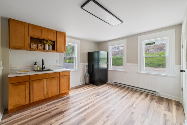 253 N Main St, Norwich, CT 06360 - kitchen with a baseboard heating unit, freestanding refrigerator, a sink, a wainscoted wall, and light wood finished floors