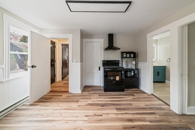 253 N Main St, Norwich, CT 06360 - kitchen with black appliances, wall chimney range hood, wainscoting, light wood finished floors, and a baseboard radiator