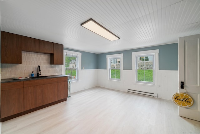 253 N Main St, Norwich, CT 06360 - kitchen with a baseboard heating unit, a wainscoted wall, a sink, light wood-type flooring, and dark countertops