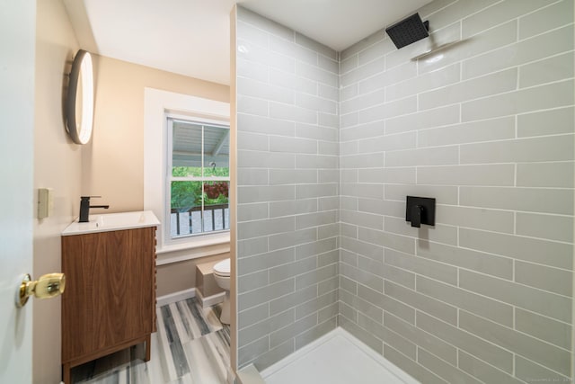 253 N Main St, Norwich, CT 06360 - bathroom featuring vanity, toilet, a tile shower, wood finished floors, and baseboards