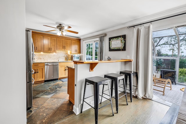 239 Bellevue Ave, West Haven, CT 06516 - kitchen with stainless steel appliances, a sink, ceiling fan, a breakfast bar area, and ornamental molding