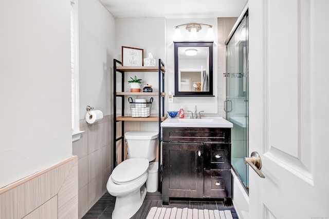 239 Bellevue Ave, West Haven, CT 06516 - bathroom featuring toilet, vanity, combined bath / shower with glass door, and tile walls