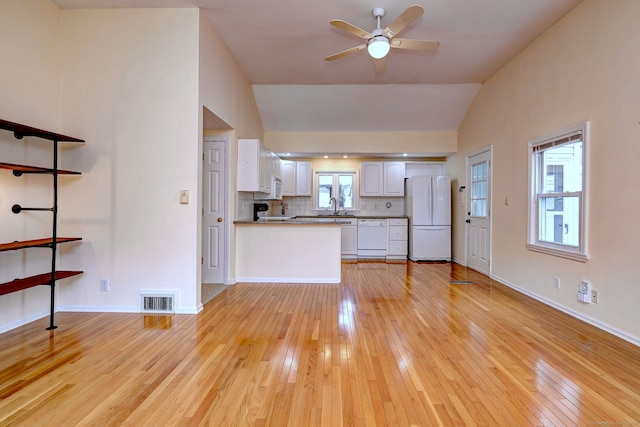 unfurnished living room with light wood-type flooring, lofted ceiling, a sink, ceiling fan, and baseboards