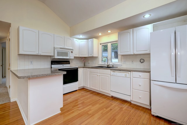 kitchen with white appliances, a sink, light wood-style floors, white cabinets, and lofted ceiling