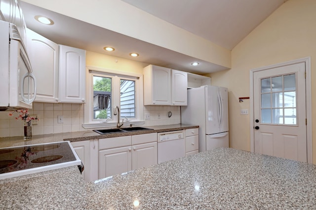 kitchen featuring white appliances, a sink, tasteful backsplash, white cabinets, and lofted ceiling