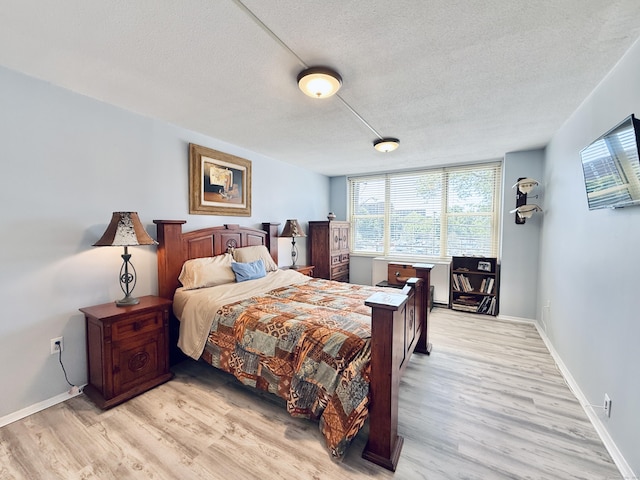 1 Strawberry Hill Ct Apt 1A, Stamford, CT 06902 - bedroom featuring a textured ceiling, light wood-style floors, multiple windows, and baseboards