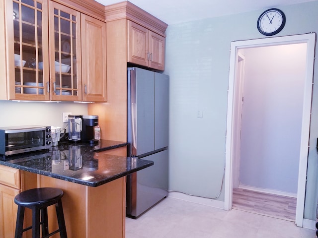1 Strawberry Hill Ct Apt 1A, Stamford, CT 06902 - kitchen featuring freestanding refrigerator, a kitchen bar, light brown cabinets, and glass insert cabinets