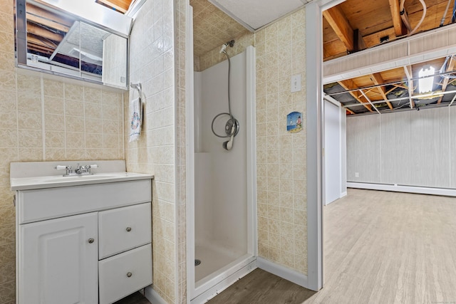 654 Beach Pond Rd, Voluntown, CT 06384 - bathroom with wood finished floors, a shower stall, tile walls, vanity, and a baseboard radiator
