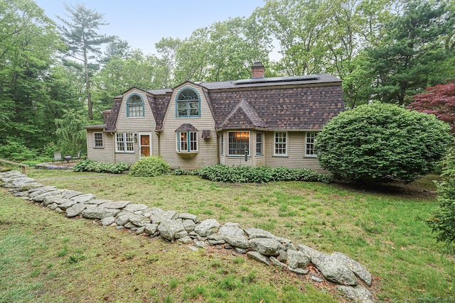 9 Pheasant Ln, Brooklyn, CT 06234 - colonial inspired home featuring a chimney, solar panels, a front yard, a gambrel roof, and roof with shingles