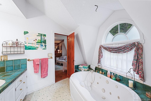 9 Pheasant Ln, Brooklyn, CT 06234 - ensuite bathroom featuring vaulted ceiling, a jetted tub, vanity, and a textured ceiling