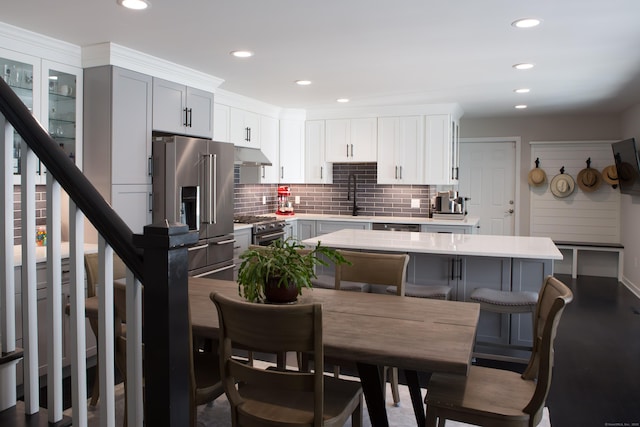 504 Harvest Commons Unit 504, Westport, CT 06880 - kitchen featuring premium appliances, a sink, under cabinet range hood, light countertops, and tasteful backsplash