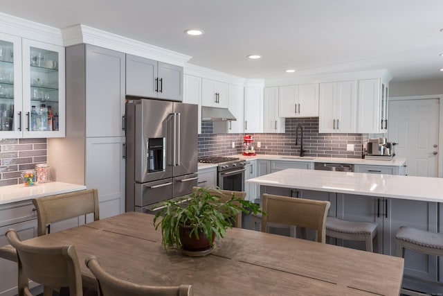 504 Harvest Commons Unit 504, Westport, CT 06880 - kitchen with high quality appliances, a sink, under cabinet range hood, a breakfast bar area, and backsplash