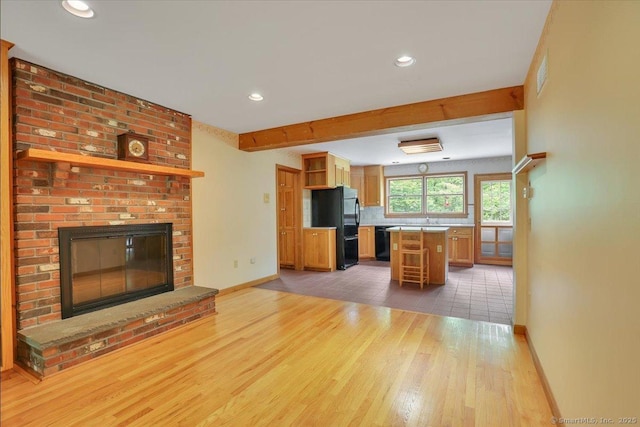 1155 Arbutus St, Middletown, CT 06457 - kitchen featuring open shelves, light wood-type flooring, black appliances, baseboards, and a brick fireplace