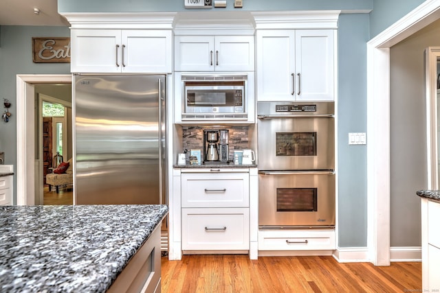 10 Grove Hill Rd, Woodbridge, CT 06525 - kitchen featuring built in appliances, dark stone countertops, light wood-style flooring, and white cabinetry