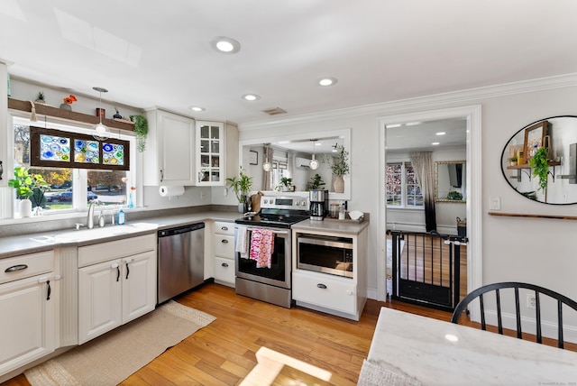 17 Saint Thomas St, Enfield, CT 06082 - kitchen featuring appliances with stainless steel finishes, a sink, ornamental molding, glass insert cabinets, and white cabinetry