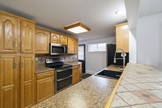 53 Roosevelt Blvd, Enfield, CT 06082 - kitchen featuring appliances with stainless steel finishes, backsplash, a sink, a textured ceiling, and brown cabinets