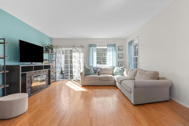 living room with wood finished floors, a glass covered fireplace, and baseboards