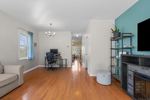 living room with a chandelier, wood finished floors, a desk, a fireplace, and baseboards
