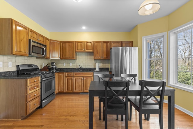 kitchen with appliances with stainless steel finishes, decorative backsplash, light wood-type flooring, and brown cabinetry