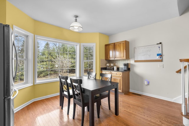 dining space with light wood-type flooring and baseboards