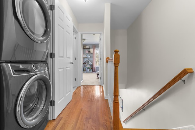 clothes washing area with stacked washer / dryer and light wood-style floors
