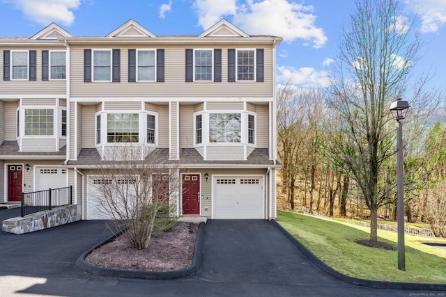townhome / multi-family property with driveway, an attached garage, and a front yard