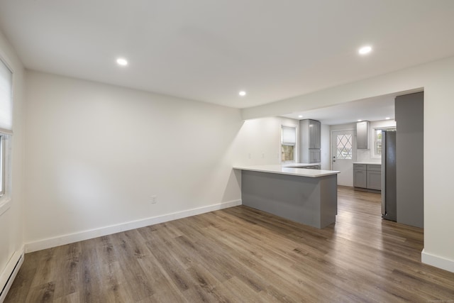 53 Kalish Ave, Enfield, CT 06082 - kitchen with baseboard heating, a peninsula, recessed lighting, wood finished floors, and gray cabinetry