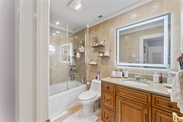 1095 Hope St Unit B, Stamford, CT 06907 - bathroom featuring tile walls, ornamental molding, toilet, vanity, and bath / shower combo with glass door