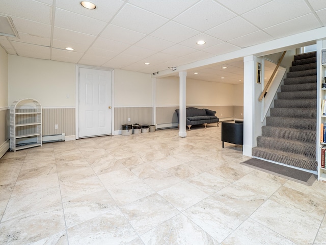 finished below grade area with stairs, baseboard heating, a wainscoted wall, and recessed lighting