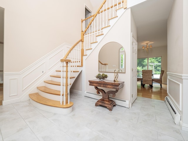 staircase with baseboard heating, a decorative wall, and a chandelier