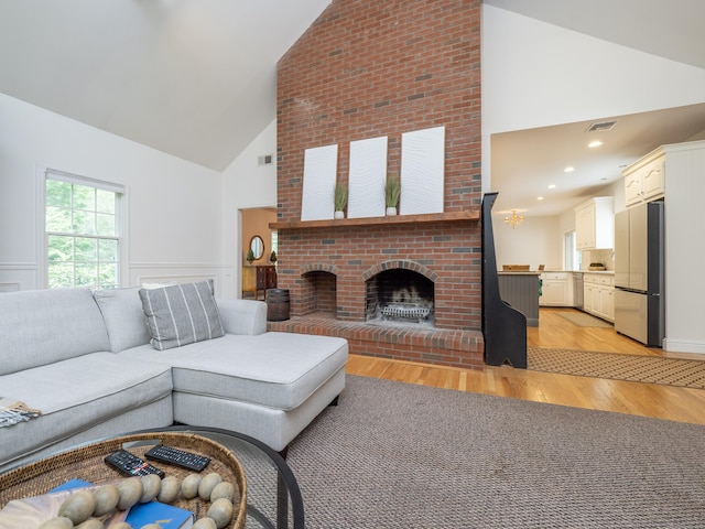 living area featuring high vaulted ceiling, a fireplace, and light wood finished floors