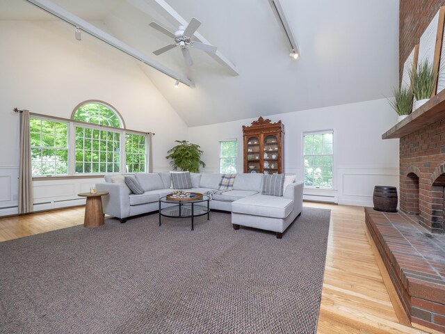 living area with track lighting, light wood-style flooring, high vaulted ceiling, beamed ceiling, and a brick fireplace
