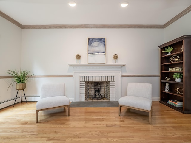 living area featuring ornamental molding, a brick fireplace, wood finished floors, and recessed lighting