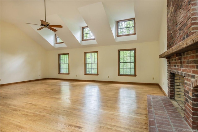 4665 Black Rock Tpke, Fairfield, CT 06824 - unfurnished living room featuring high vaulted ceiling, a skylight, a brick fireplace, plenty of natural light, and light wood-style floors